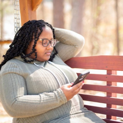 Black woman looks at her phone with concerned expression.