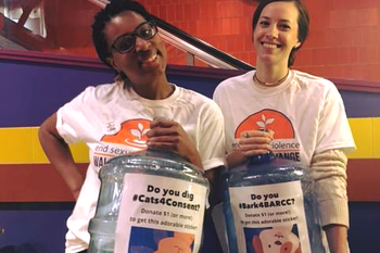 Two BARCC staffers smiling holding two large donation containers 