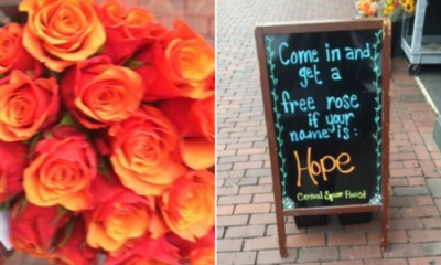 Bouquet of orange roses next to sign that says Come in for a free rose if your name is Hope
