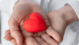 Hands holding a small red heart-shaped object.