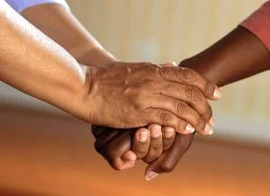 Two hands gently holding another person's hand, symbolizing how to support a survivor in your life with compassion and connection.