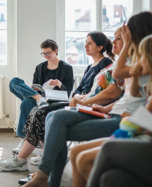 A group of people sitting together in a line, looking at someone out of frame.