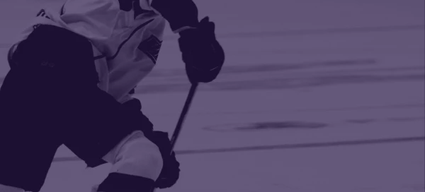 A hockey player in action on the ice, seen from the side, holding a stick and focused on a puck during an intense game in Boston.