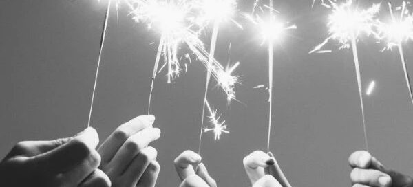 Hands holding sparklers against a gray sky, a moment of light symbolizing hope and resilience. Remember, if in need, services like a rape crisis center are always there to provide support and get help whenever it's needed most.