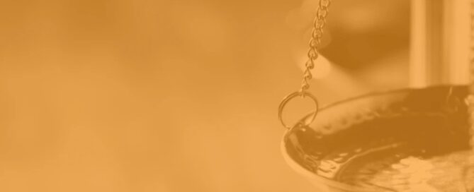 Close-up of a balance scale with a focus on one of the scale pans, symbolizing the balance of services and support, set against an orange-tinted background.