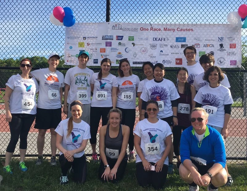 running-race-fundraising-photo Group of people in matching t-shirts posing in front of a banner at a charity race event.