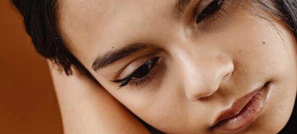 A close-up of a person resting their head on their crossed arms, looking down thoughtfully, as if deciding to get help at the Boston crisis center.