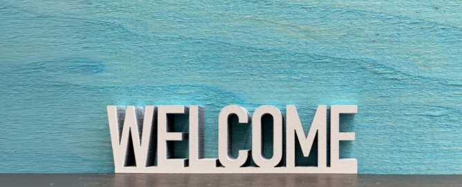 3D letters forming the word "WELCOME" against a blue wooden background, setting the tone for our new website launch at barcc.org.