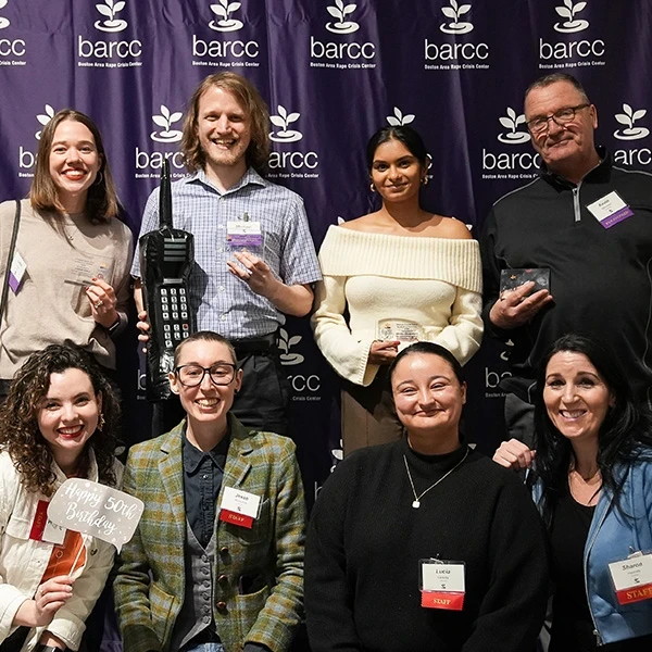 BARCC Event Group of people wearing green and purple "Walk for Change" shirts, standing on a wet path in front of houses, smiling and posing for a photo.