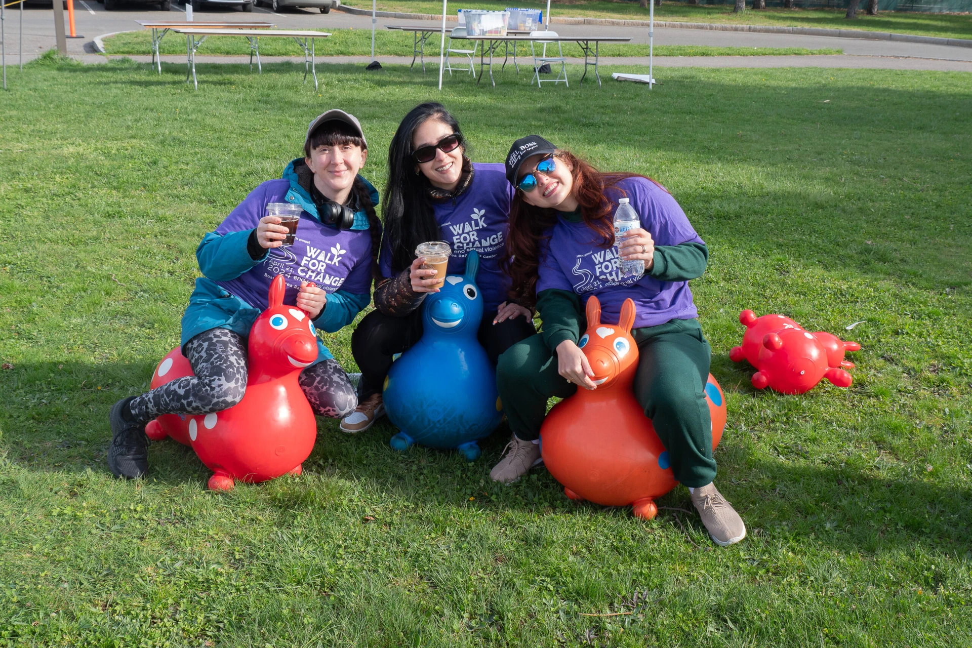 Group of people wearing green and purple "Walk for Change" shirts, standing on a wet path in front of houses, smiling and posing for a photo.