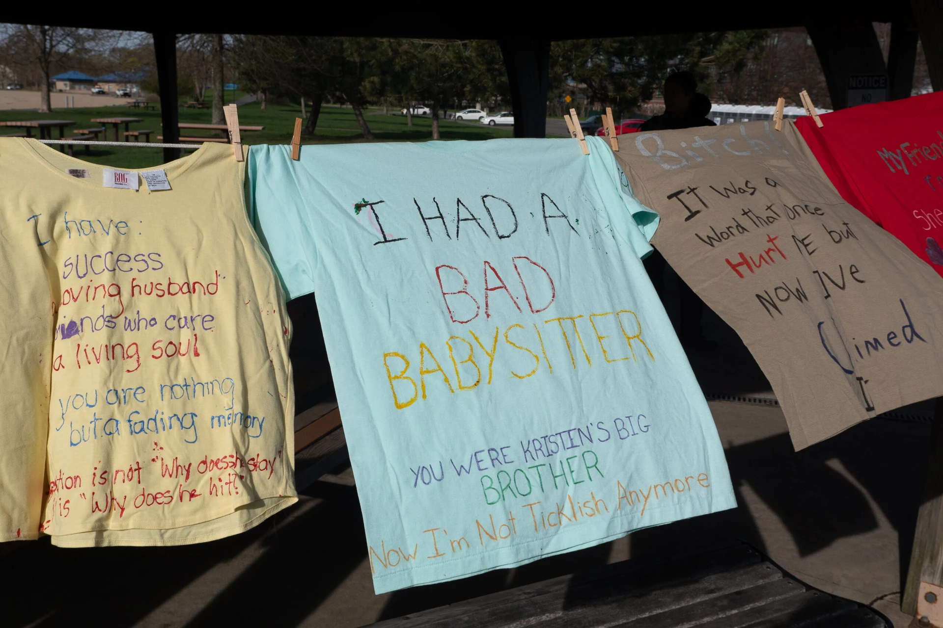 T-shirts sway gently on the line, each bearing messages about personal experiences related to babysitters, abuse, and family. Reach out to a local rape crisis center in Boston to get help and support for those affected by these profound stories.